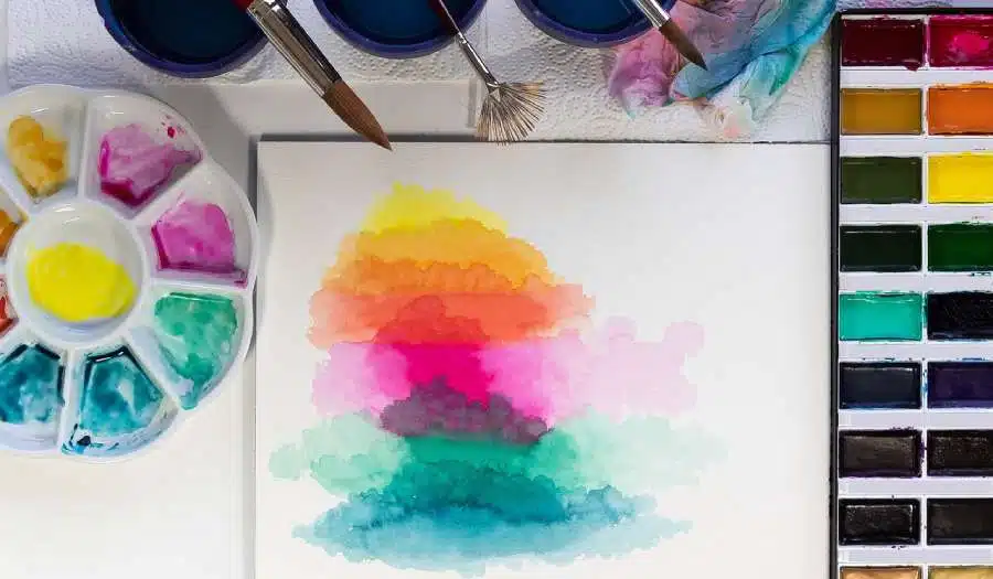 watercolor pallets alog with brushes and colors on the paper