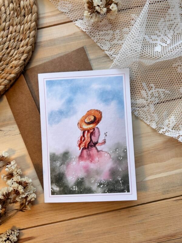 back of the girl with a hat sitting in the field holding flower in her one hand on greeting card