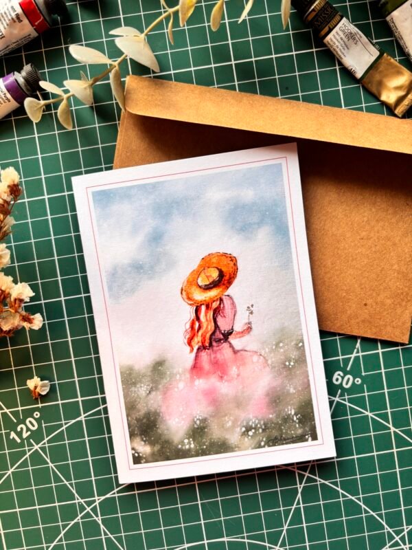 back of the girl with a hat sitting in the field holding flower in her one hand