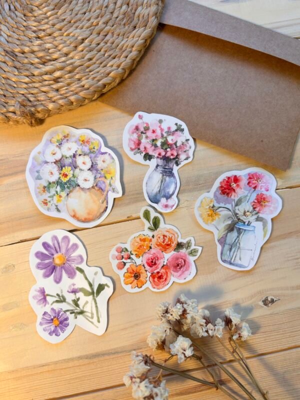 five floral stickers on the table along with brown envelope and dry white flowers