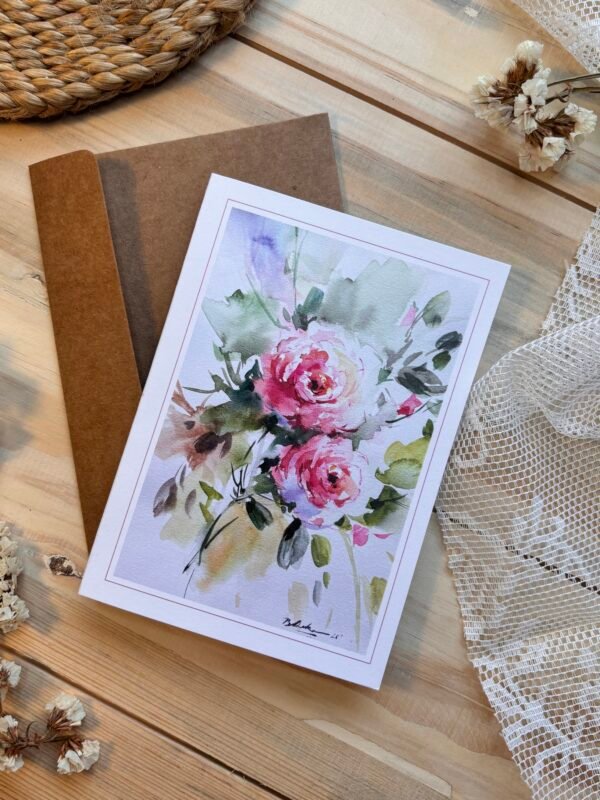 greeting card of 2 pink roses on top of brown envelope on the table