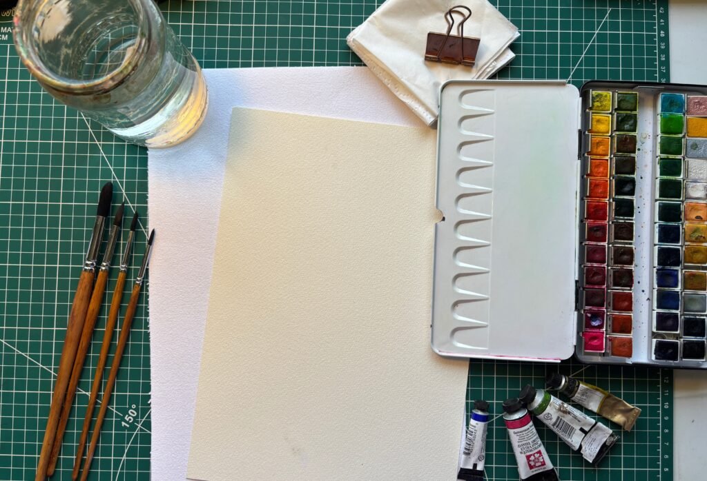 Watercolour painting starter materials - artist-grade paints, round brushes, cold-pressed paper, and water jar